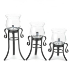 Three lovely candle stands in three sizes pack a triple-powered punch of style for any room. The black metal stands have curled flourishes and the fluted clear candle cups will let the light of your favorite candles shine brightly.