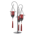 Instantly create an atmosphere of intrigue and romance! Tasseled metal cages swing gently from a slender central holder; glass votive cups in a deep garnet hue bestow ordinary candlelight with an air of enchantment.