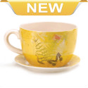 Drink in the beauty of your favorite plant with this charming teacup planter. The sunny yellow teacup features a botanical design with postcard style and the matching saucer completes the look. Drain hole at bottom of teacup. 2 separate pieces.