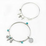 This charm bracelet set will be your favorite go-to fashion statement. Two silvery bangles feature a variety of darling charms, from a Celtic heart to a collection of beautiful crosses, and turquoise beads. Wear them together or separate.